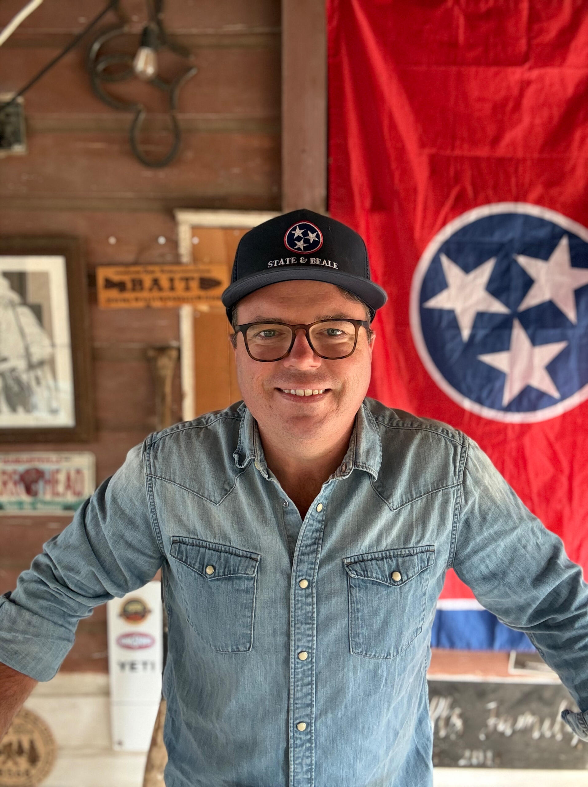 Toby Sells wearing a State and Beale cap in front of the Tennessee flag